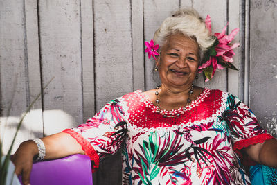 Portrait of smiling woman standing against wall