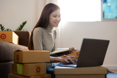 Young woman using laptop while sitting on sofa at home