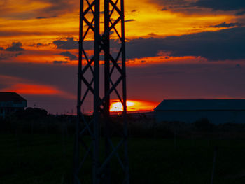 Silhouette built structure on field against sky during sunset