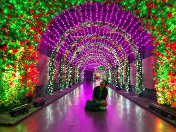 Rear view of woman walking in illuminated tunnel