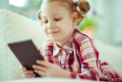 Close-up of smiling girl using mobile phone