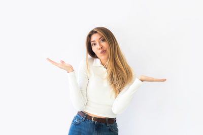 Portrait of young woman standing against white background