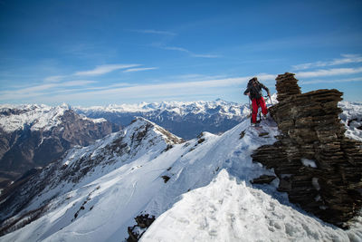 Man hiking on snowcapped mountain against sky