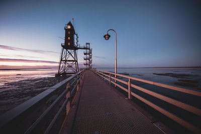 Pier over sea against sky during sunset