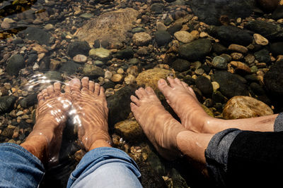 Low section of couple sitting in river