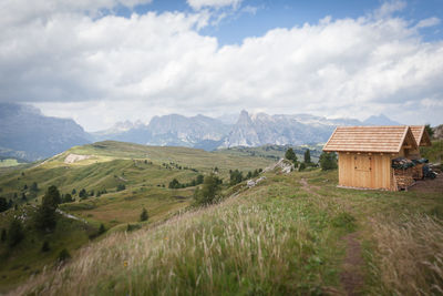 House on field by mountain against sky