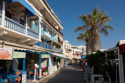 Street amidst palm trees and buildings against sky