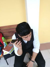 High angle view of young man using mobile phone while sitting on bench