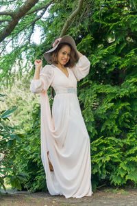 Portrait of smiling young woman standing against trees