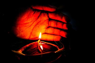 Close-up of lit candle in darkroom