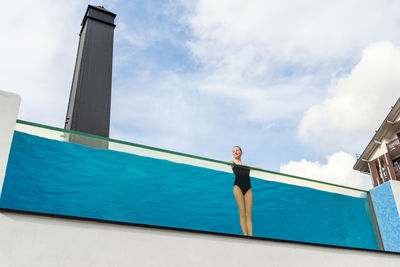 Low angle view of woman standing in swimming pool against sky