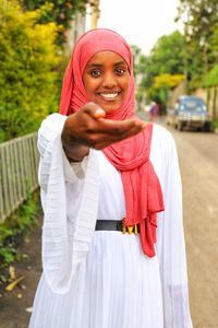 Portrait of young woman standing against trees