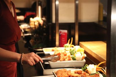 Midsection of woman having food in restaurant