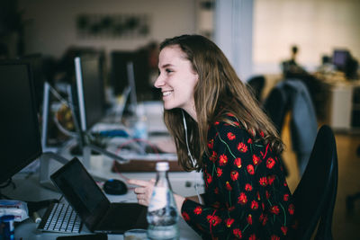 Young woman using mobile phone while sitting on table