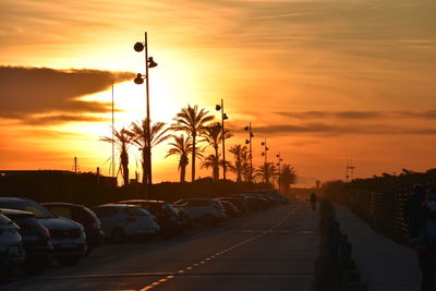 Cars on road against sky during sunset