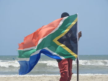 Man flag on beach against clear sky