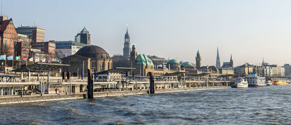 View of buildings by river in city against clear sky