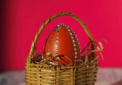 Homemade orange easter egg in easter nest against pink background