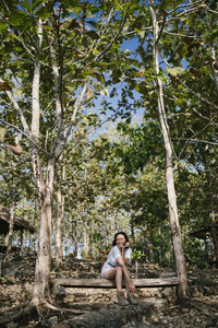 Side view of man sitting on tree trunk