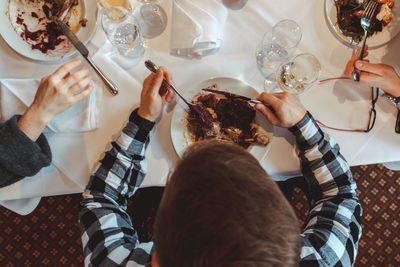 High angle view of man rating and drinking wine at table