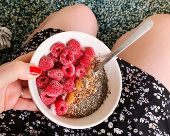 High angle view of hand holding strawberries in bowl