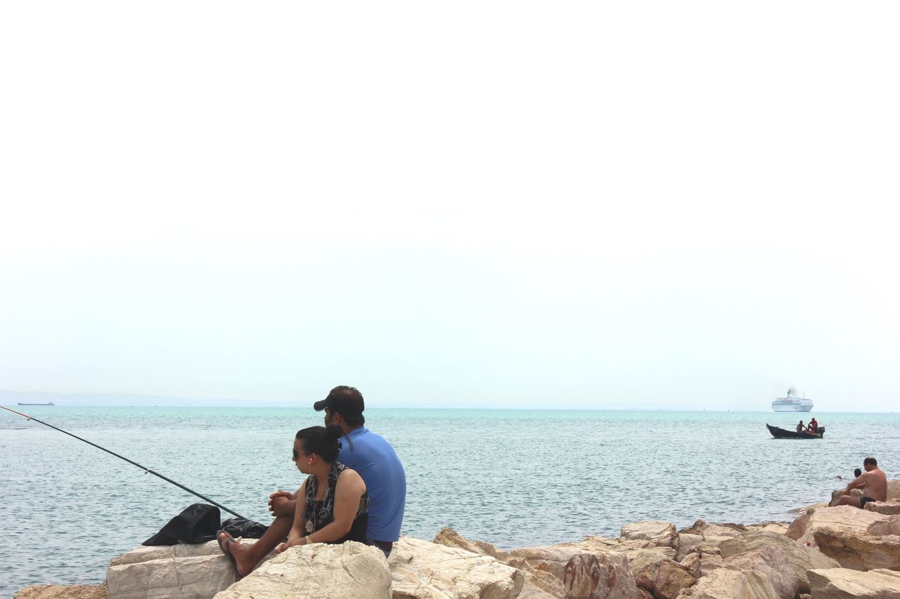 sea, water, horizon over water, lifestyles, clear sky, copy space, transportation, nautical vessel, sitting, men, leisure activity, mode of transport, tranquility, boat, scenics, tranquil scene, rear view, beauty in nature