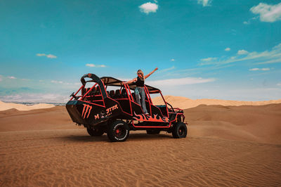 Young woman on land vehicle in desert against sky