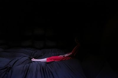 Woman lying down on bed against black background