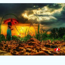 Woman standing on field against cloudy sky