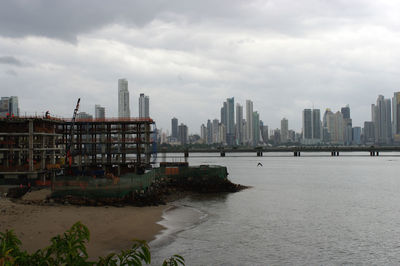 City buildings by sea against sky