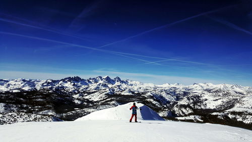 Man skiing on snowcapped mountain against blue sky