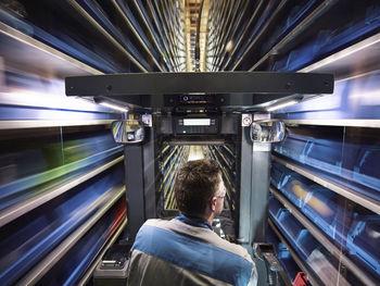 Worker operating high rack in storehouse