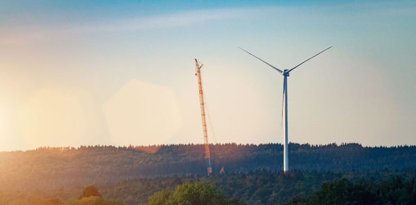 Wind turbines on field against sky