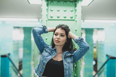 Young woman looking away while standing against column