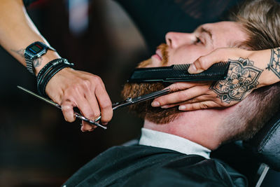 Close-up of woman shaving man beard