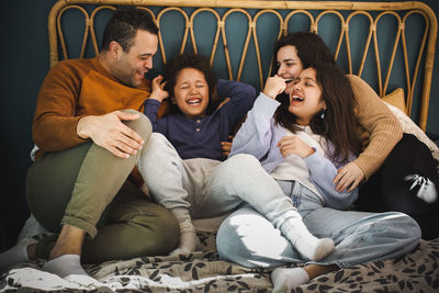 Happy family enjoying together while sitting on bed at home