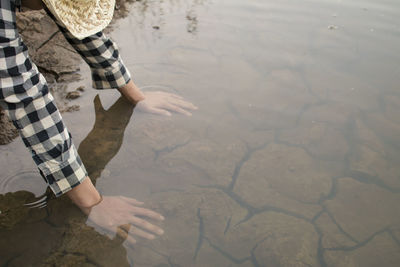 Cropped image of person touching lake with hands