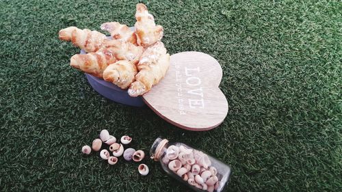 High angel view of croissants in container by heart shape with shells over field