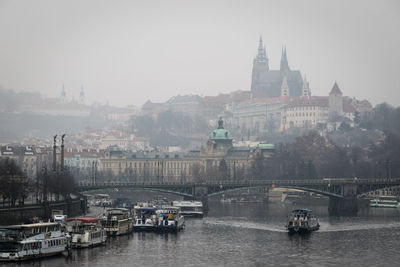 Boats in river by buildings in city