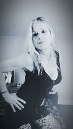 Portrait of young woman standing against wall