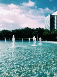 Swimming pool by trees against sky