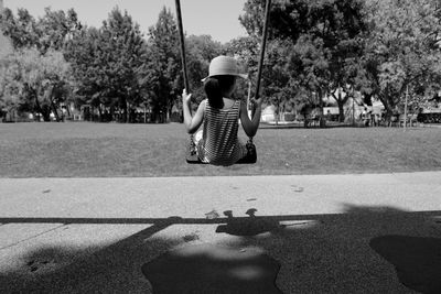 Rear view of girl sitting on swing at playground