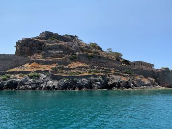 Rock formation in sea against clear sky