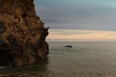 Rock formation on beach against sky during sunset