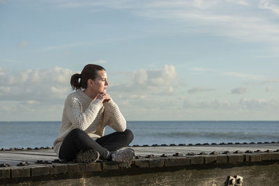 Woman sitting outdoors by the ocean, enjoying the view.