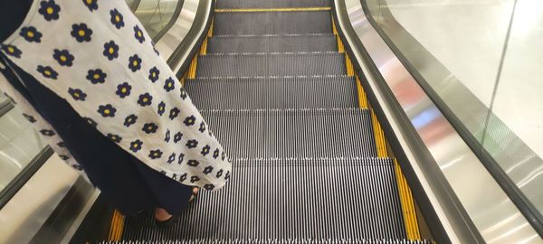 Low section of woman on escalator at subway station