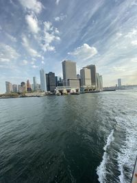 City buildings by sea against sky