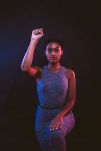 Portrait of woman standing against black background