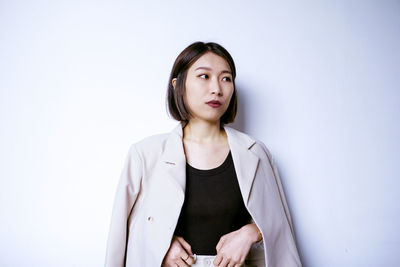 Portrait of young businesswoman standing against white background