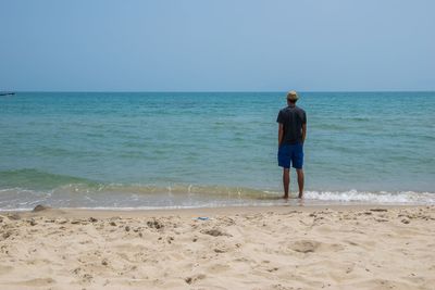 Rear view of man on beach against clear sky